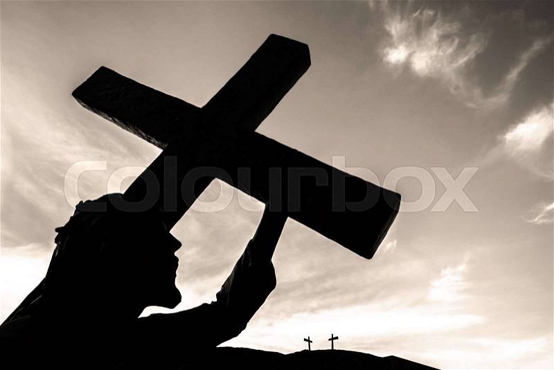 Bronze statue of Jesus carrying his cross, on the way to his crucifixion. Ideal for the easter concept, resurrection and other. Sky with clouds on background, stock photo