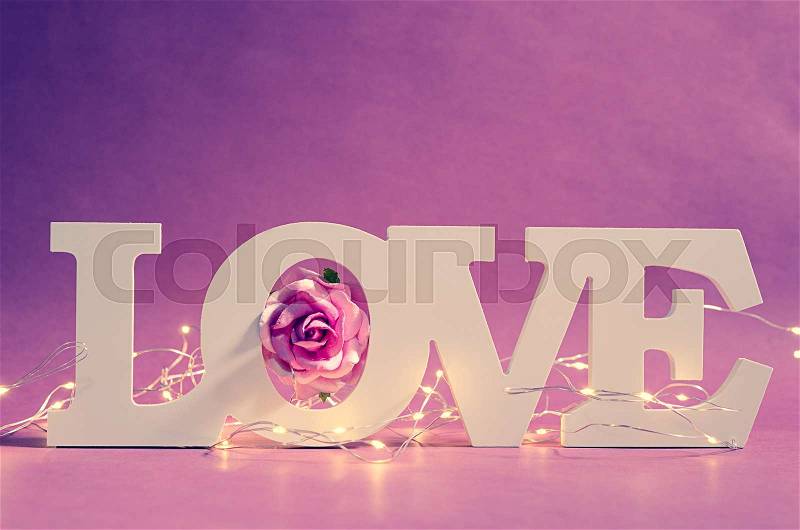 White love text wood and led light with pink rose on wooden background. Valentine concept, stock photo