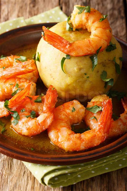 Mofongo (Garlic-Flavored Mashed Plantains): a very tasty dish served with shrimp close-up on a plate on the table. Vertical, stock photo