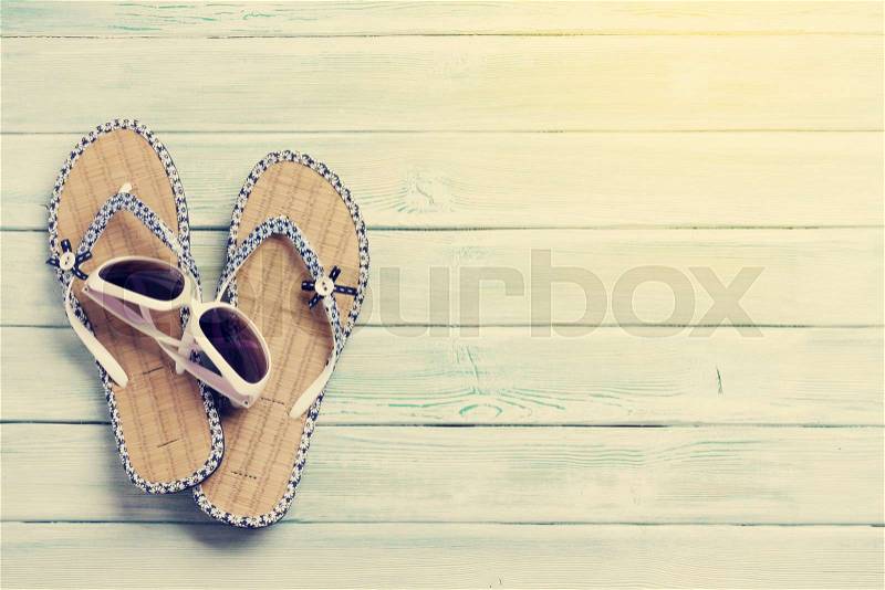Travel vacation background concept with sunglasses and flip flops on wooden backdrop. Top view with copy space. Flat lay. Sunny toned, stock photo