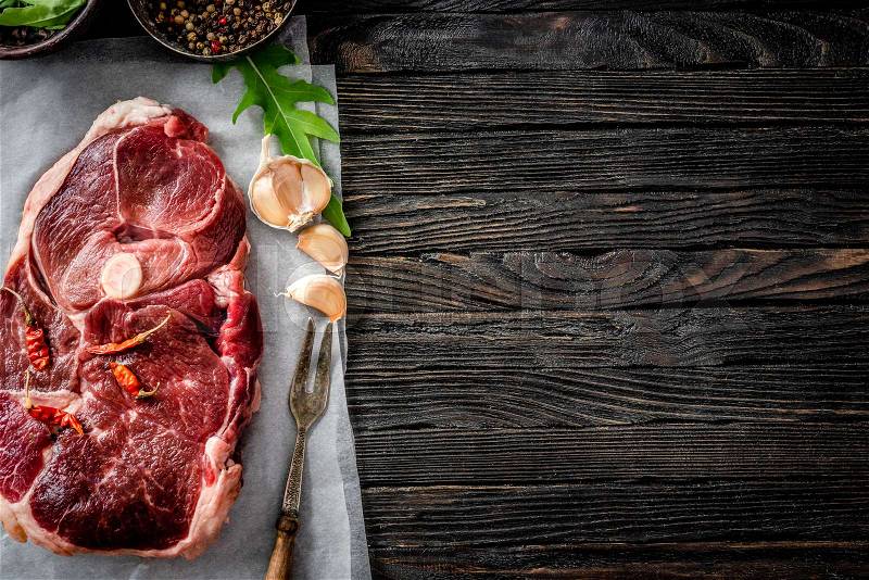Piece of raw lamb meat with spices on dark wooden table, top view, stock photo