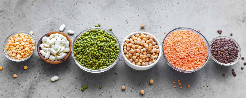 Assortment of colorful legumes in bowls, lentils, kidney beans, chickpeas, mung, peas on grey background, banner. Healthy food, dieting, nutrition concept, vegan ..., stock photo