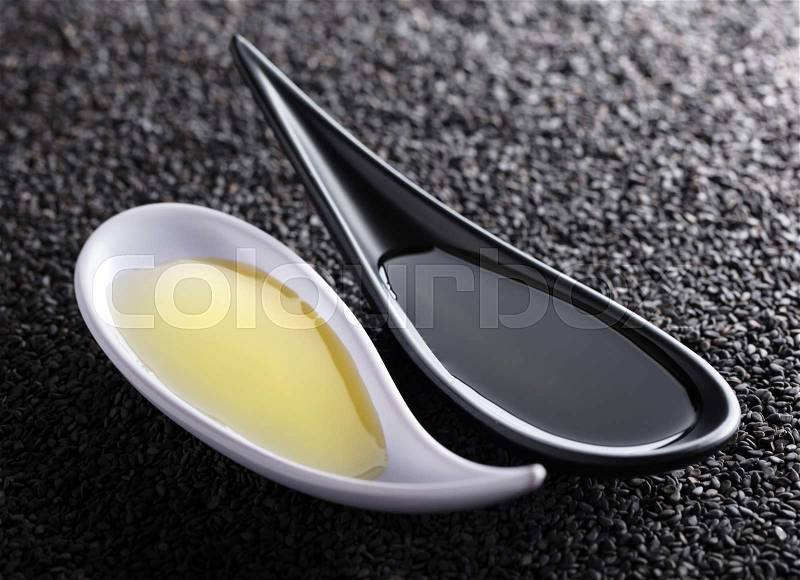 Sesame oil in small bowls on a background of black sesame. Used in medicine and cooking, stock photo