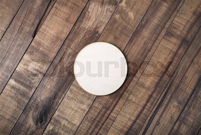 Blank wooden beer coaster on wood table background. Flat lay, stock photo