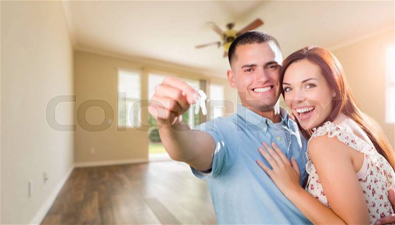 Young Military Couple with House Keys In Empty Room of New Home, stock photo