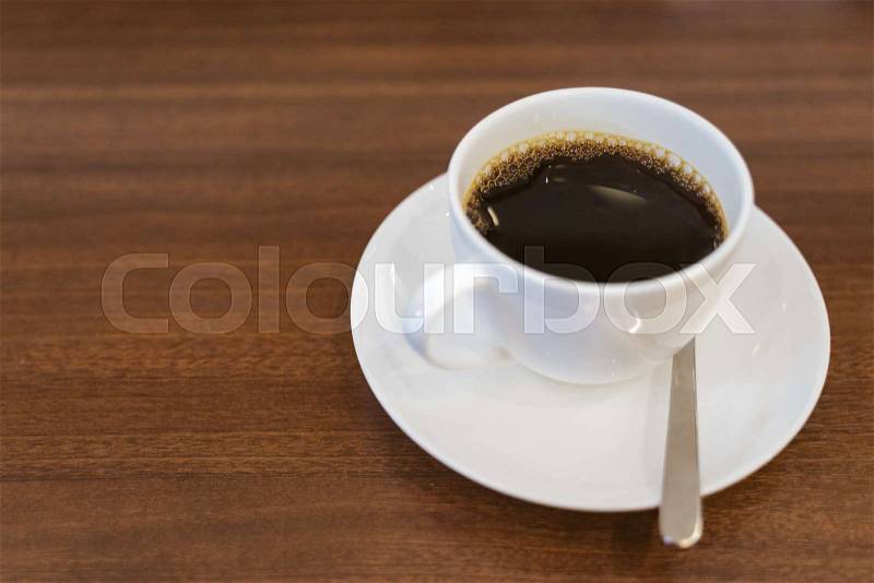 Close up hot espresso with bubbles in white coffee cup on wood table near window in coffee shop in the morning in vintage soft tone, black caffeine to stay awake for ..., stock photo