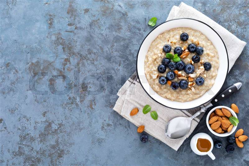 Oatmeal with fresh raw blueberry, almond nuts and honey for breakfast. Healthy vegetarian food. Top view, stock photo
