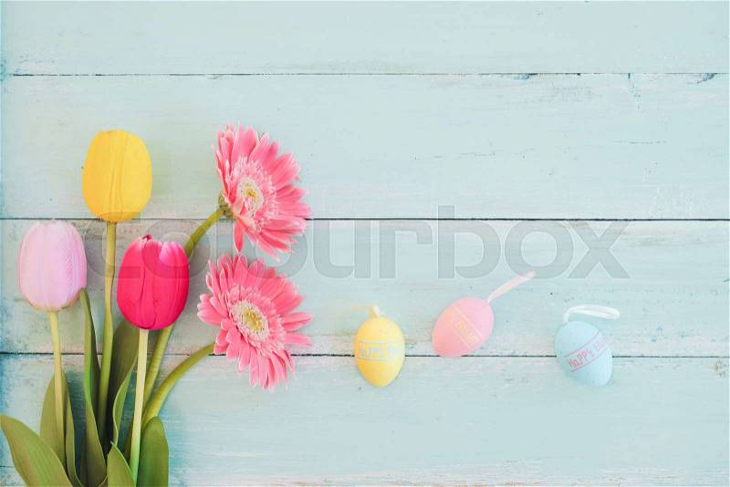 Colorful Easter eggs with tulip flower on rustic wooden planks background. Holiday in spring season. vintage pastel color tone. top view composition, stock photo