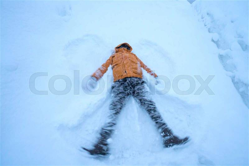 Happy man lying down on the snow in winter, stock photo