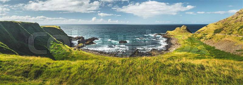 Panoramic overview of the Northern Ireland shoreline. Amazing Irish landscape. Green grass covered shore surrounded by the ocean water. Cozy bay under the cloudy sky ..., stock photo