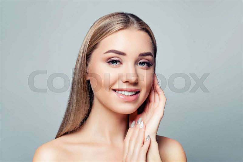 Pretty girl smiling on gray background. Facial treatment, skin care and cosmetology concept, stock photo