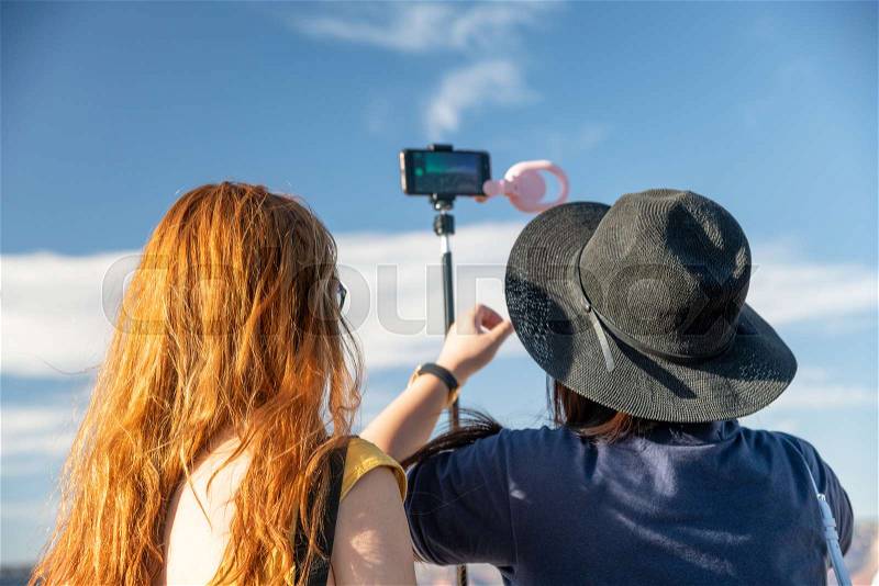 Back view of two women photographing national park with smartphone and monopod, stock photo