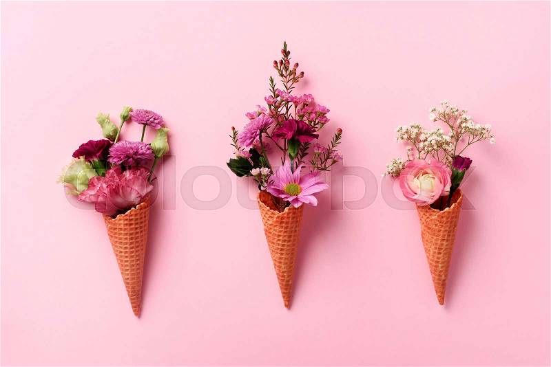Summer minimal concept. Ice cream cone with pink flowers and leaves on punchy pastel background. Flat lay. Top view. Creative layout, stock photo