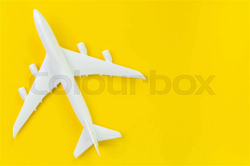White toy commercial airplane on solid yellow background using as travel and transportation business wallpaper, stock photo