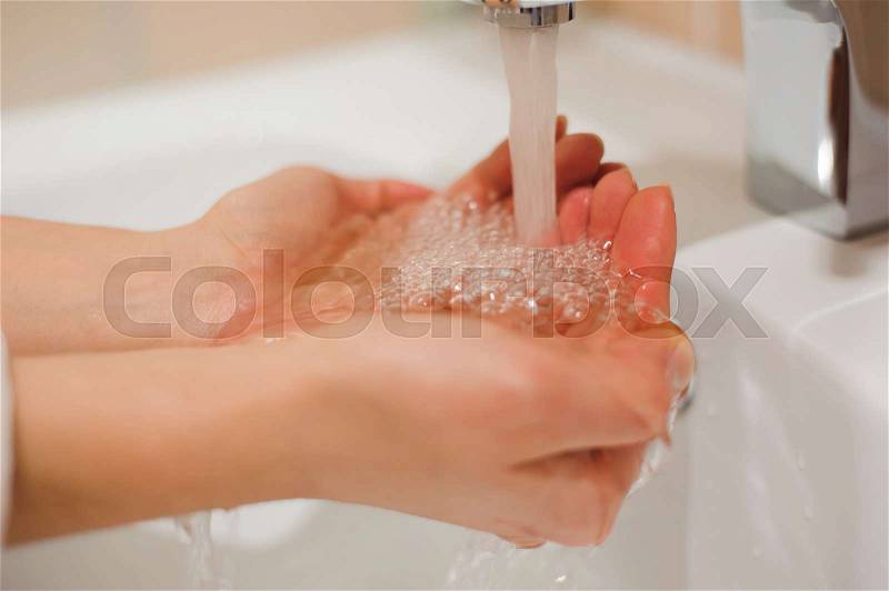 A woman washing her hands in the sink, stock photo