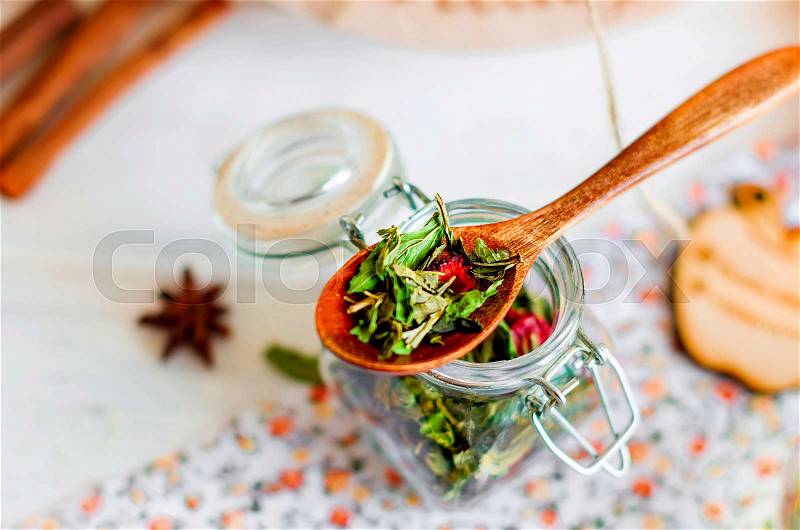 Dry mint and strawberry tea in wooden spoon on glass jar with dry tea close up, top view, natural light, selective focus, stock photo
