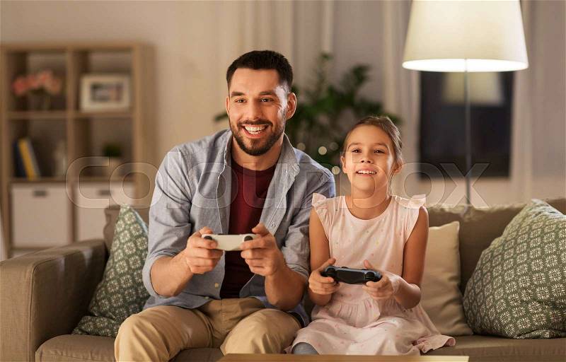 Family, gaming and entertainment concept - happy father and little daughter with gamepads playing video game at home, stock photo