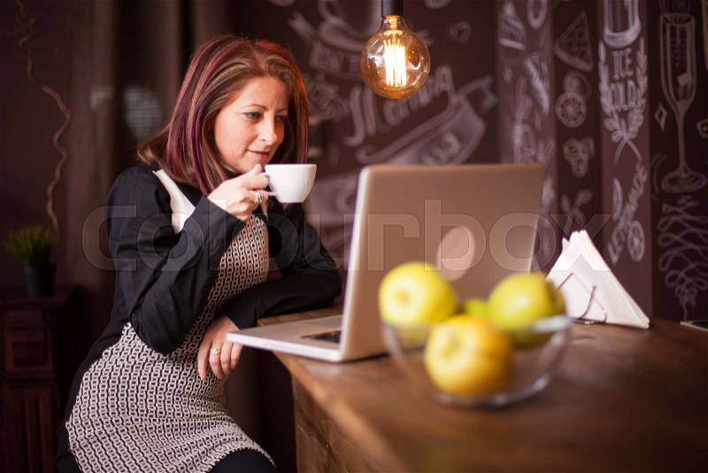Entrepreneur woman enjoying her coffee in front of her laptop. Relaxing in a vintage coffee shop, stock photo