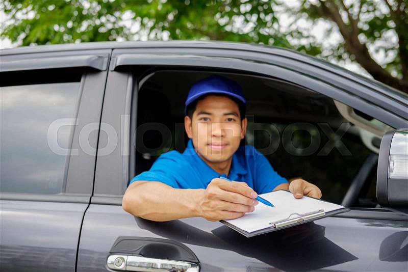 Delivery driver driving van with parcels on seat outside warehouse, stock photo