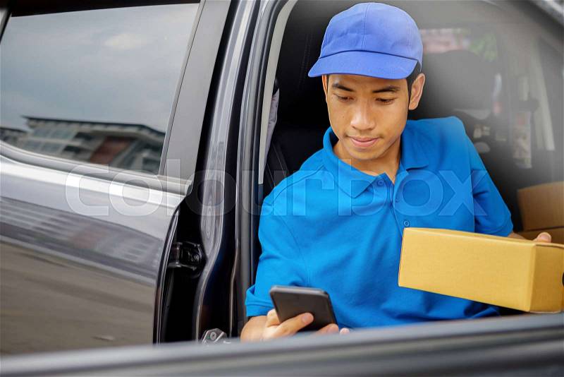 Delivery driver driving van with parcels on seat outside warehouse, stock photo