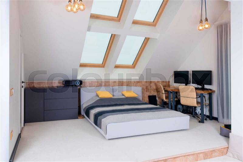 King-size bed with yellow and grey bedding in modern bedroom. Stylish room interior with comfortable bed and workplace, stock photo