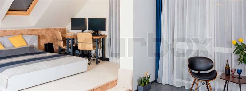King-size bed with yellow and grey bedding in modern bedroom. Stylish room interior with comfortable bed and workplace, stock photo
