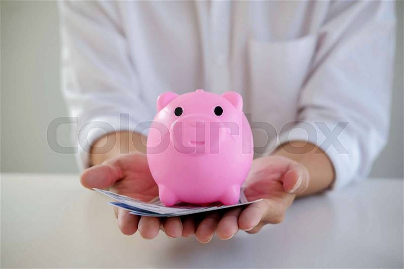 Business people sheltering coins and piggy bank at desk. saving concept, stock photo