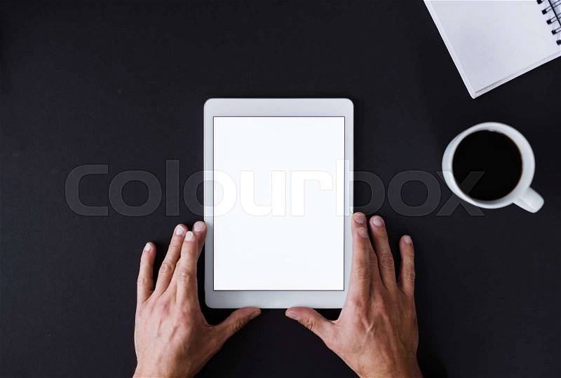 A top view of male hands holding tablet on a desk. A copy space, stock photo