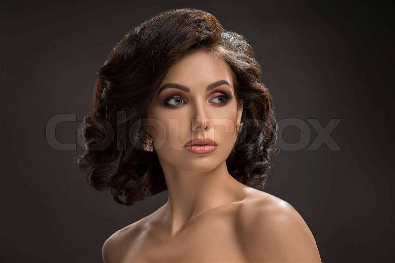 Sexy young stylish lady with volumed, curly hair, long eyelashes, puffy lips, perfect skin, glowing eye shadow and naked shoulders looking away. Glamour model posing ..., stock photo