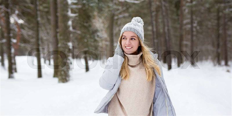 Portrait of young beautiful woman walking in winter forest, stock photo