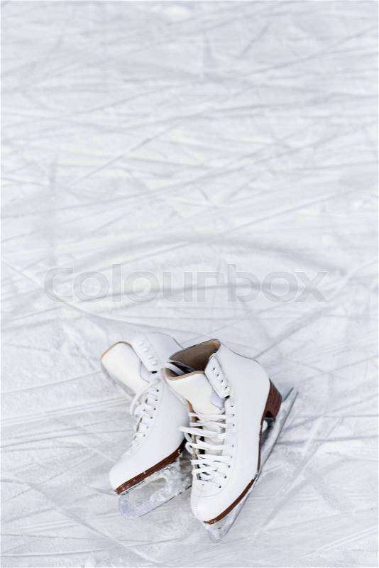 Close up of white figure skates over ice background with marks from skating or hockey, stock photo