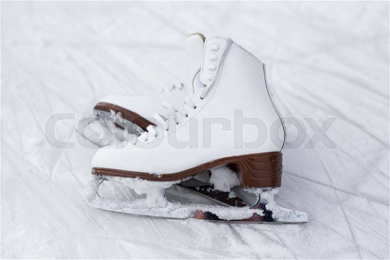 Close up of figure skates over ice background with marks from skating, stock photo