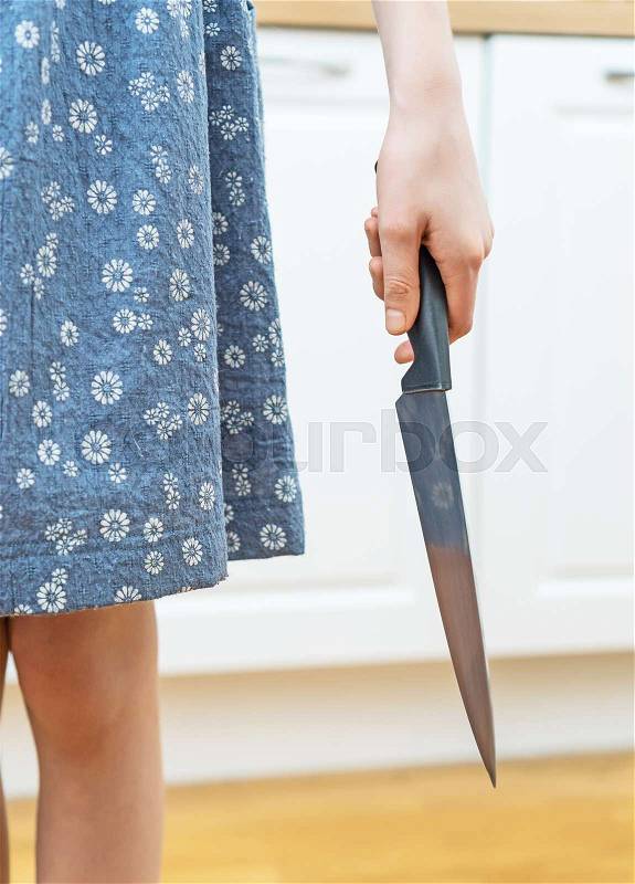 Dangerous situation in the kitchen. Child with kitchen knife in hand, stock photo