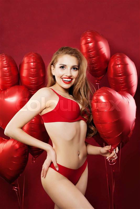 Excited woman with balloons red heart. Sexy model girl in red sensual underwear. Valentine\'s day concept . Positive emotion. Expressive facial expressions, stock photo