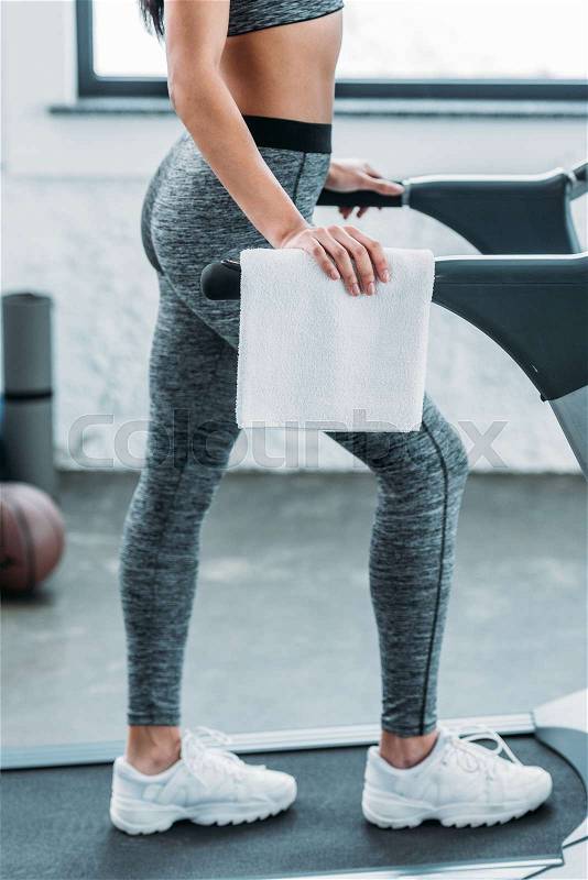 Low section of african american girl in sportswear exercising on treadmill in gym, stock photo