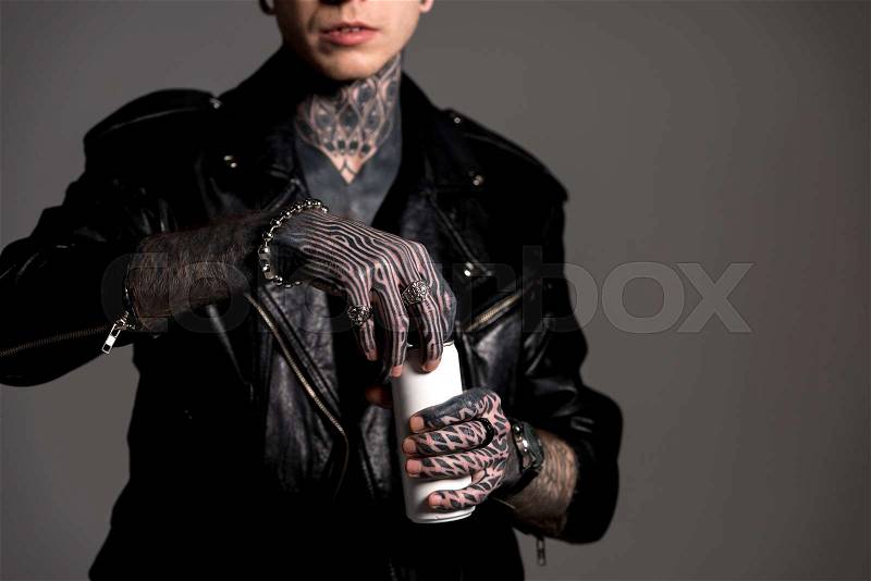 Cropped shot of tattooed man in leather jacket opening soda can isolated on grey, stock photo
