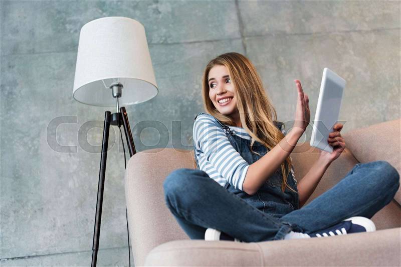 Young girl smiling and turning away from monitor of digital tablet, stock photo