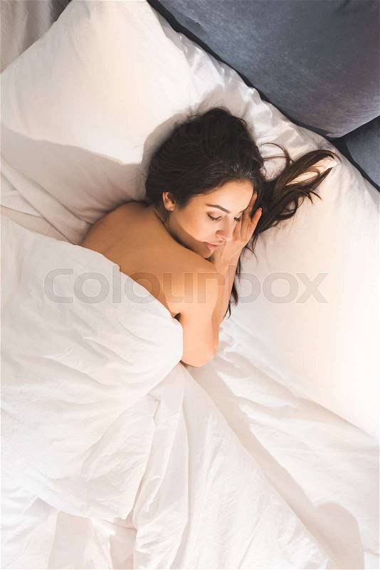 Beautiful nude woman sleeping in bed at home in morning, stock photo
