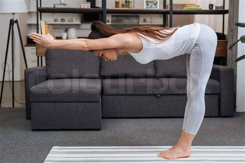 Young woman practicing yoga pose at home in living room, stock photo