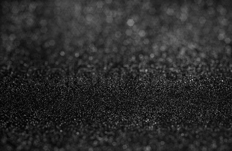 Selective focused at textured of black glitter background with hexagon shape bokeh defocused, stock photo