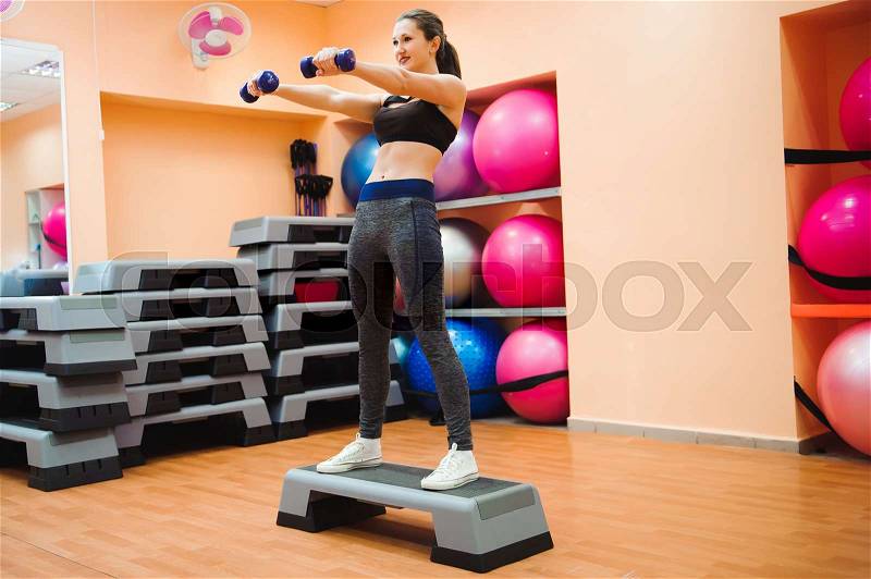 Athletic woman trainer doing aerobic class with steppers. Sport and health concept, stock photo