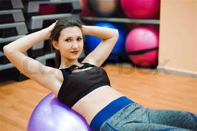 Pretty sexual straight fitness woman with musculat body lying on big ball in sport hall training indoor, horizontal picture, stock photo