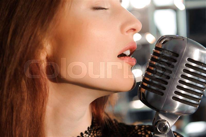 Rock star. Sexy Girl singing in retro microphone, stock photo