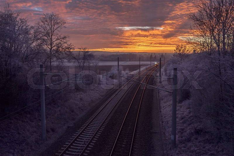 Winter sunrise and the rail tracks passing through frozen nature, near the german town, Schwabisch Hall, stock photo