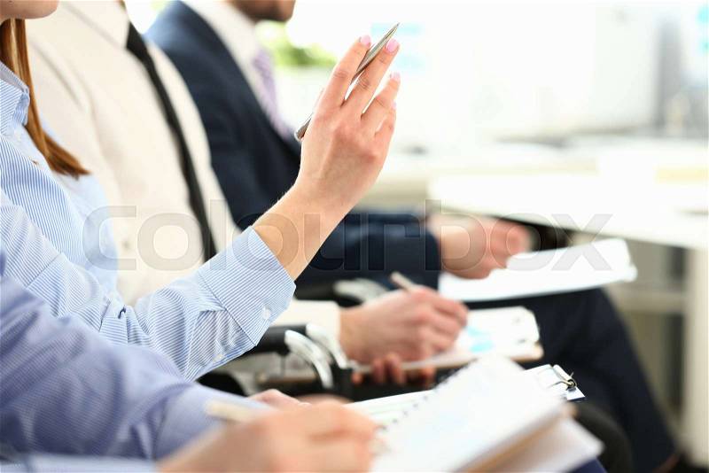 Female hand is raised up with silver pen in hall for an event conference asks to choose job interview concept, stock photo