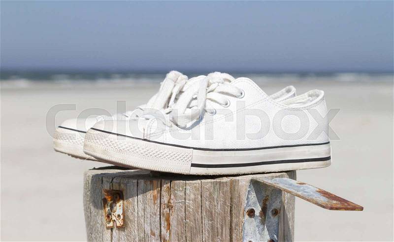 White sneaker shoes on a pole - At the beach, stock photo