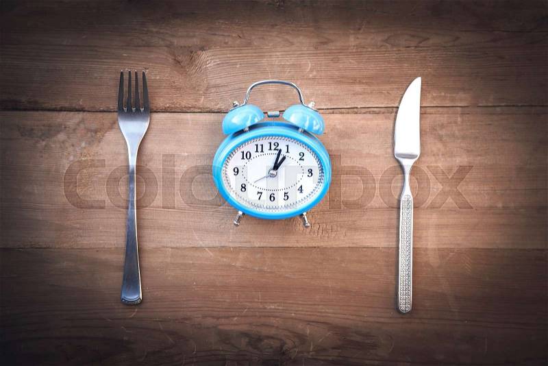 Alarm clock with fork and knife on the table. Time to eat, stock photo