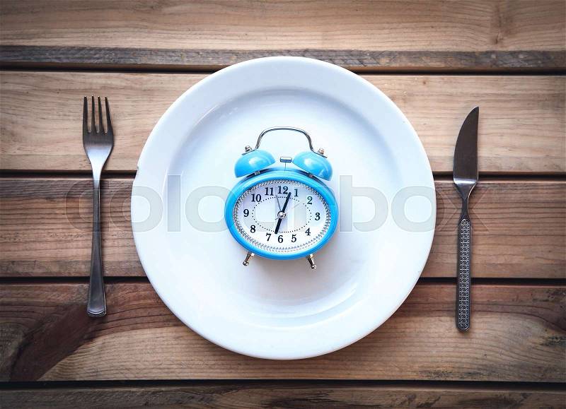 Alarm clock with fork and knife on the table. Time to eat, stock photo