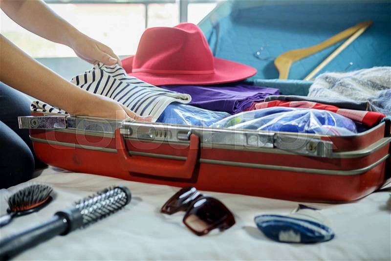 People packed suitcase with travel accessories on bed. Vacation concept, stock photo
