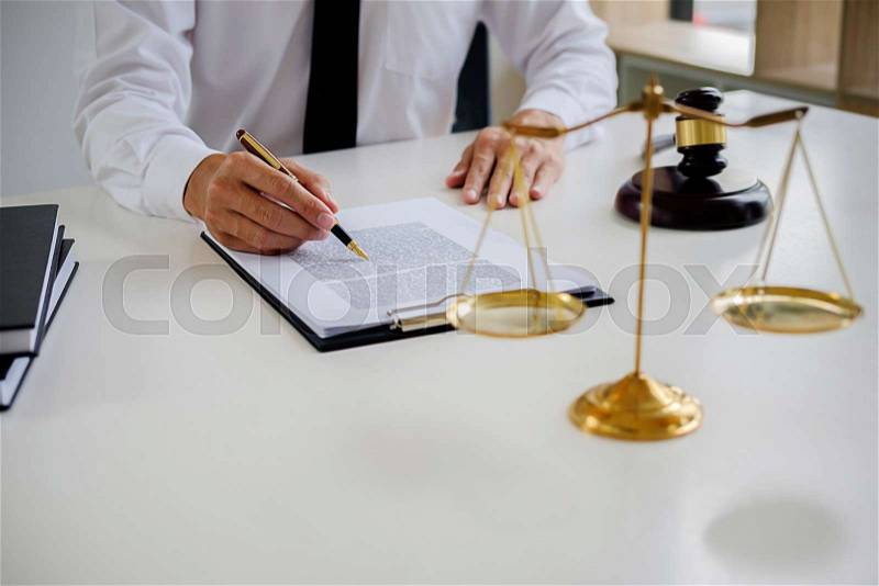 Justice and Law concept. Legal counsel presents to the client a signed contract with gavel and legal law or legal having team meeting at law firm in background, stock photo